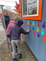 Giddens School student adding their handprint to the check-in house at the developing Henderson THV in Rainier Beach
