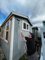 Transcarent volunteer adding a fresh coat of paint to a tiny house at Interbay Tiny House Village